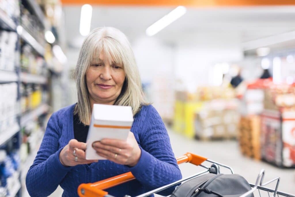 Gray haired lady reading the ingredients on a box in the supermarket - chabybucko getty images signature