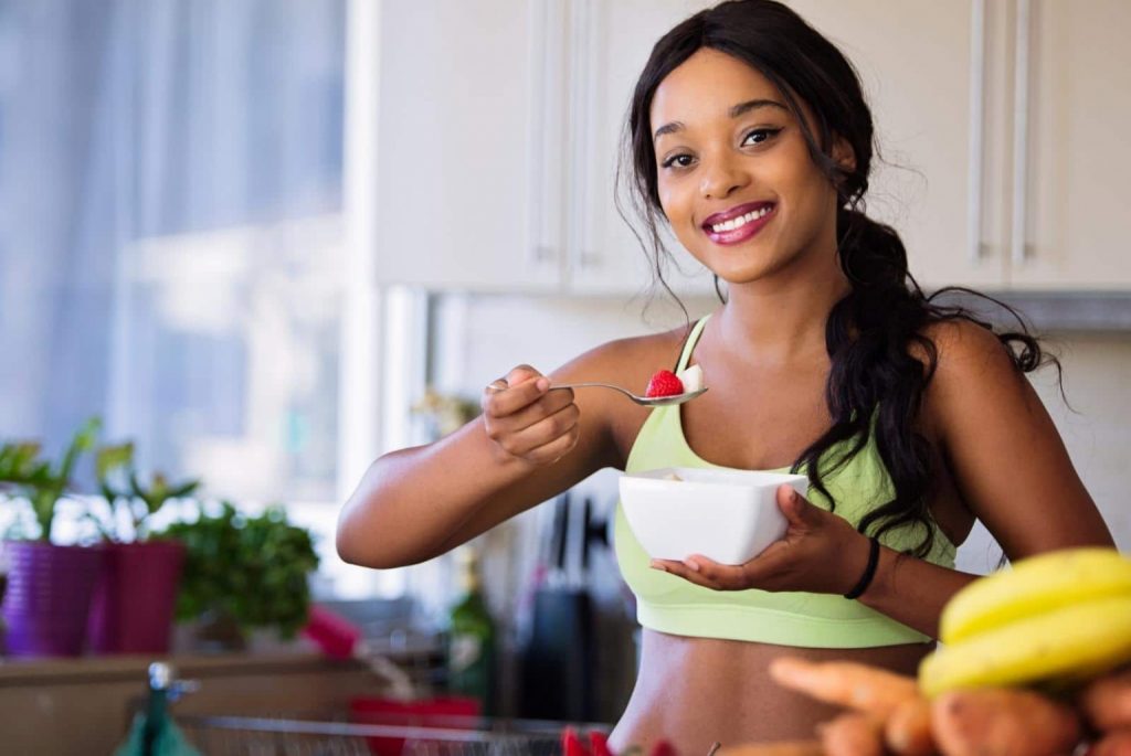 Healthy young woman of color wearing workout clothes and eating a salad