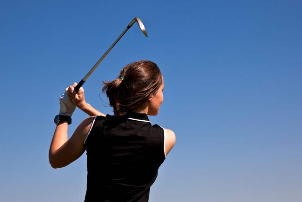 Young woman swinging a golf club fitzer - getty images